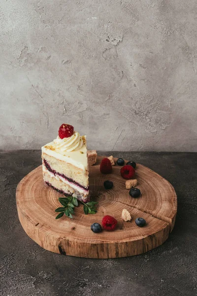 Pedazo de delicioso pastel afrutado con crema batida en tablero de madera - foto de stock