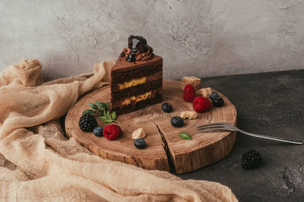 Vista de cerca de pastel de chocolate dulce sabroso con bayas en el tablero de madera - foto de stock