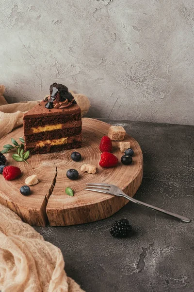 Vista de cerca de delicioso pastel de chocolate con bayas en tablero de madera - foto de stock