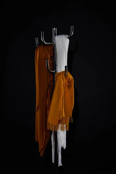 Різні шарфи, що звисають на стелажі для пальто ізольовані на чорному — стокове фото