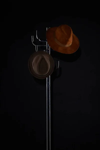 Hats hanging on coat rack isolated on black — Stock Photo