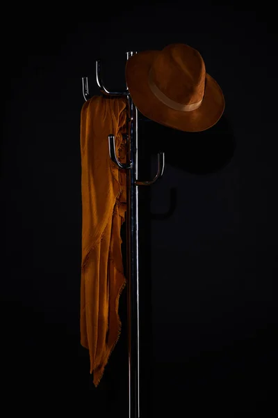 Écharpe et chapeau suspendus sur porte-manteau isolé sur noir — Photo de stock