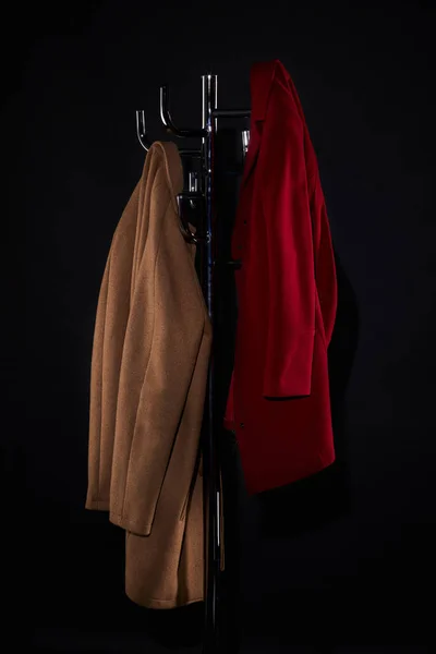 Classic coats on coat rack isolated on black — Stock Photo