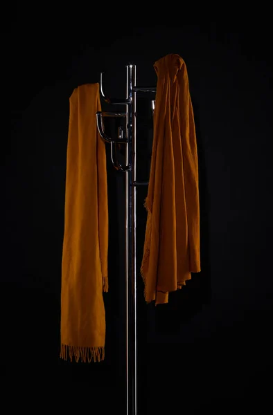 Two scarves on coat rack isolated on black — Stock Photo