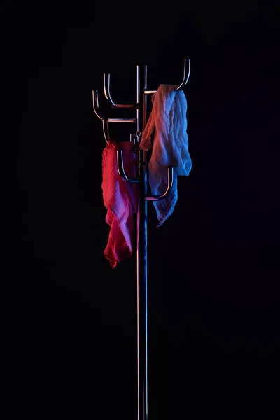 Scarf hanging on coat rack under toned light isolated on black — Stock Photo