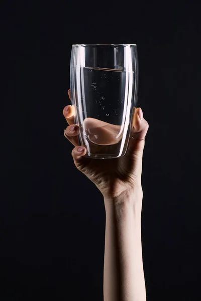 Colpo ritagliato di donna che tiene un bicchiere d'acqua isolato sul nero — Foto stock