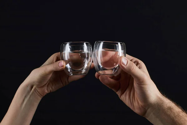 Обрізаний знімок чоловіка і жінки, що клянеться в склянці ізольовано на чорному — стокове фото