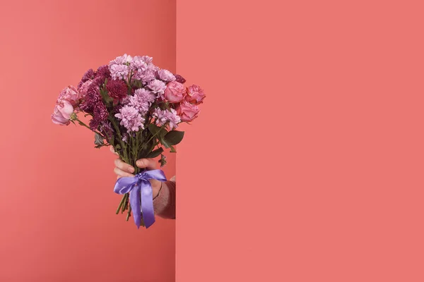 Женщина, торчащая букет цветов за стеной на красном — стоковое фото