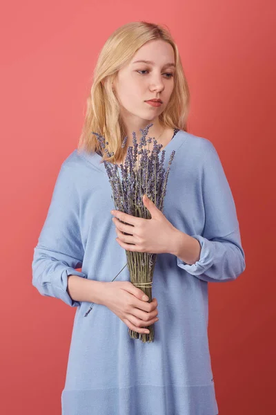 Thoughtful young woman with bouquet of lavender flowers isolated on red — Stock Photo