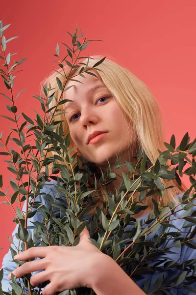 Atractiva joven con racimo de ramas de eucalipto aisladas en rojo - foto de stock