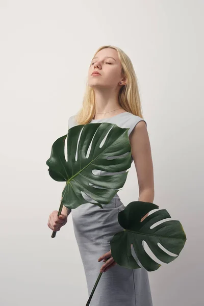 Belle jeune femme aux feuilles de monstère isolées sur blanc — Photo de stock