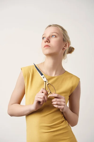 Jeune femme réfléchie avec des ciseaux à coudre isolés sur blanc — Photo de stock