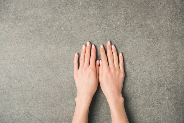 Cropped shot of female hands on grey concrete surface — Stock Photo