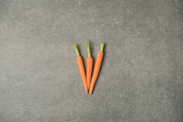 Vista superior de zanahorias maduras dispuestas en superficie de hormigón gris - foto de stock