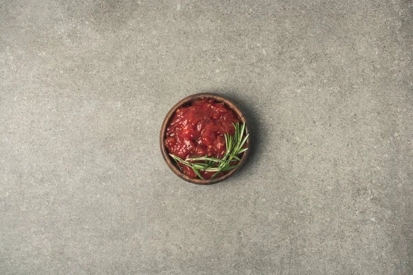 Top view of sauce with rosemary twig served in bowl on grey concrete tabletop — Stock Photo