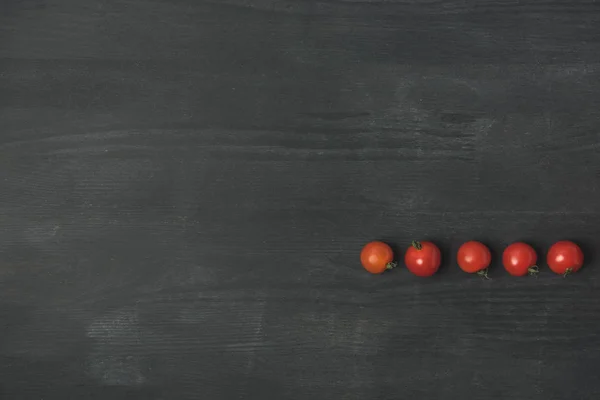 Вид зверху розташовані вишневі помідори на темно-сірій поверхні — стокове фото
