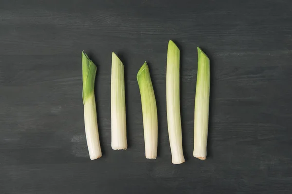 Top view of arranged fresh leek on dark tabletop — Stock Photo