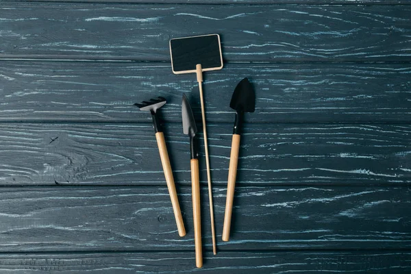 Flat lay with arranged gardening tools and empty chalkboard on wooden tabletop — Stock Photo