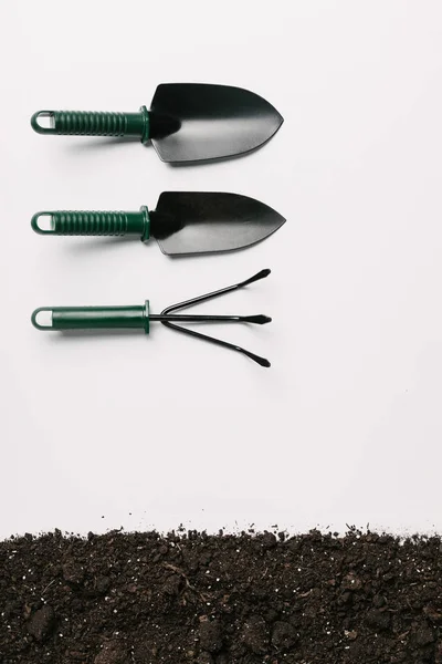 Vue de dessus des outils de jardinage disposés et du sol isolé sur blanc — Photo de stock