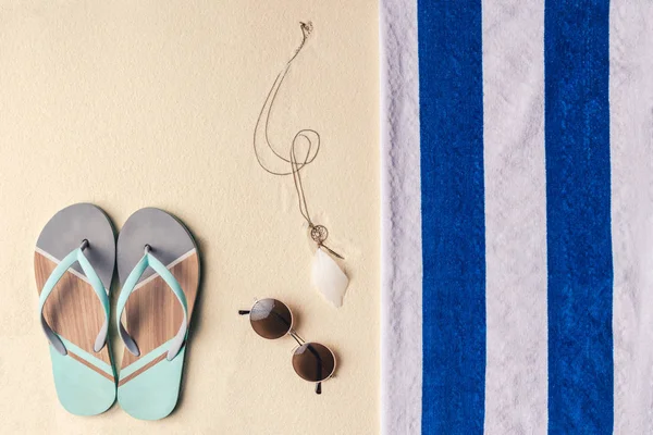 Flip Flops und Sonnenbrille per Handtuch auf hellem Sand — Stockfoto