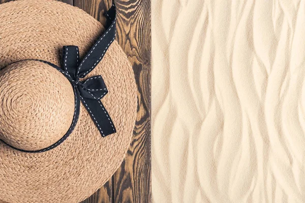 Straw hat on wooden pier on sandy beach — Stock Photo