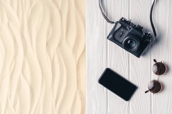 Смартфон с камерой и солнцезащитными очками на пирсе на легком песке — стоковое фото