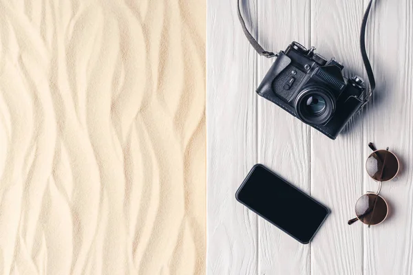 Smartphone with camera and sunglasses on pier on light sand — Stock Photo