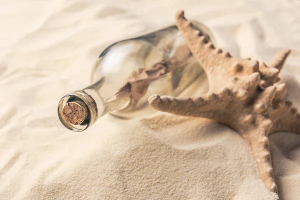 Garrafa com carta e estrela do mar na praia de areia — Fotografia de Stock