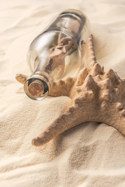 Bouteille en liège avec message et étoile de mer sur sable clair — Photo de stock