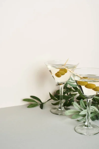 Klassische Martini-Cocktails mit Olivenzweig auf grauer Oberfläche — Stockfoto