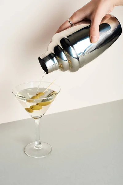 Vue recadrée de la femme versant du martini dans un shaker en verre avec des olives — Photo de stock
