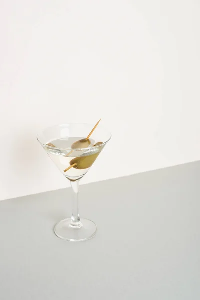 Glass of vermouth with olives on grey surface isolated on white background — Stock Photo