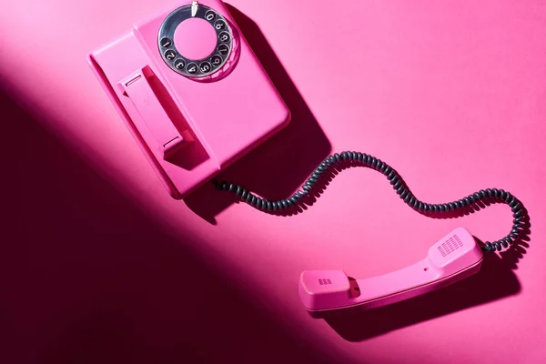 Vista superior do telefone rosa com sombra na superfície brilhante — Fotografia de Stock