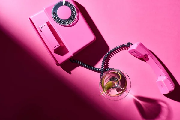 Top view of martini in glass with retro telephone on pink background — Stock Photo