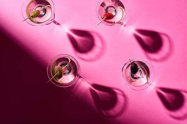 Draufsicht auf Martini-Cocktails mit Oliven auf leuchtend rosa Hintergrund — Stockfoto