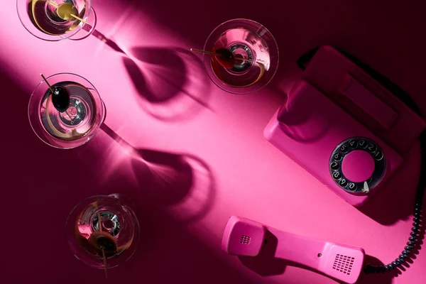 Вид сверху на коктейли мартини и ретро-телефон на розовом фоне — стоковое фото