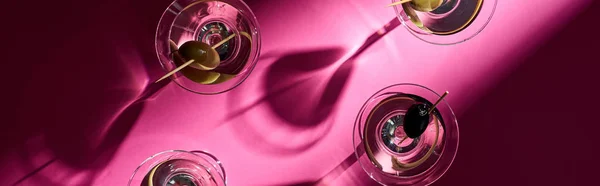 Vista superior de martini con aceitunas sobre fondo rosa brillante, plano panorámico - foto de stock