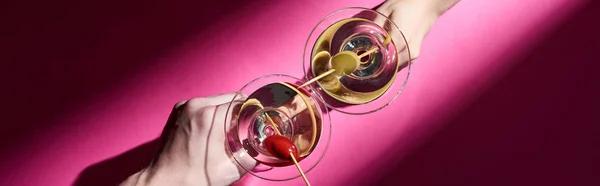 Cropped view of man and woman holding martini cocktails on pink background, panoramic shot — Stock Photo