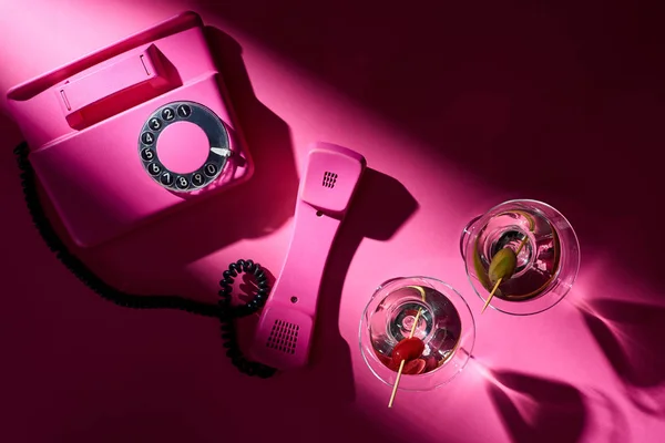 Vista dall'alto di telefono vintage e cocktail con ombra su sfondo rosa — Foto stock