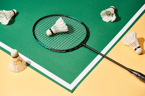 High angle view of badminton racket and shuttlecocks on green and yellow background — Stock Photo