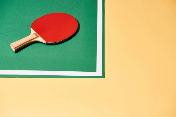 Hochwinkelaufnahme des Tennisschlägers auf Tisch auf gelber Oberfläche — Stockfoto