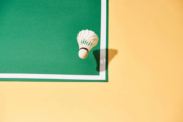 High angle view of badminton shuttlecock on green court and yellow surface — Stock Photo