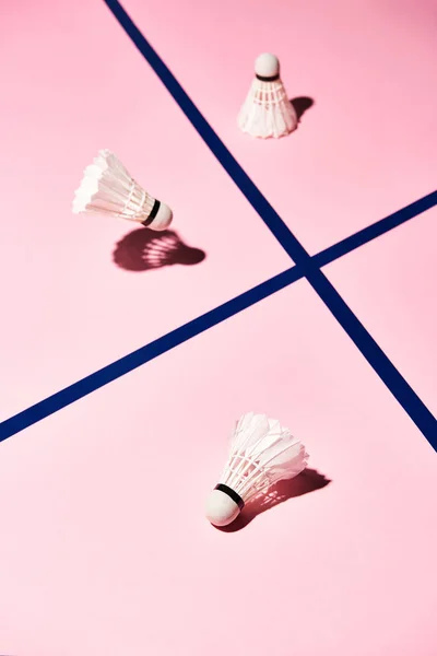 Vista en ángulo alto de las lanzaderas de bádminton en la superficie rosa con líneas azules - foto de stock