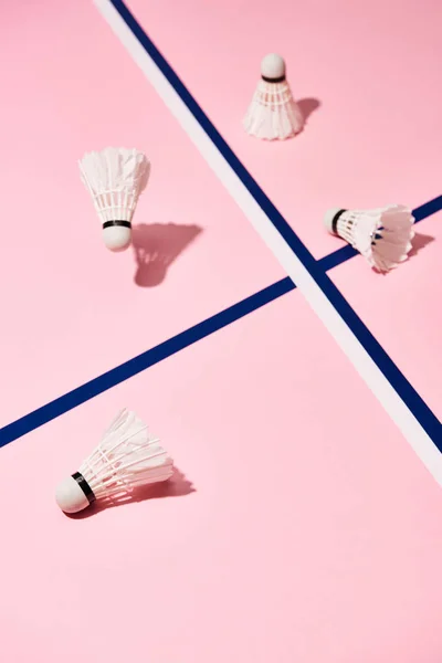 Navettes de badminton avec ombre sur surface rose avec lignes bleues — Photo de stock