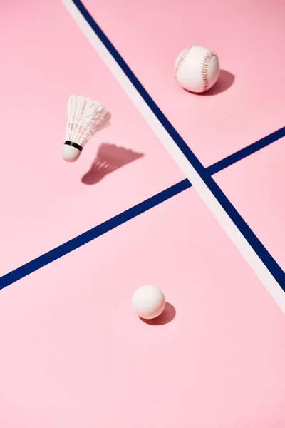 Balls for tennis, baseball and badminton shuttlecocks on pink surface with blue lines — Stock Photo