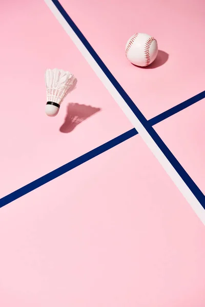 Baseball and badminton shuttlecock on pink surface with blue lines — Stock Photo