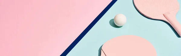 Ping pong raquetas y pelota en la superficie de pastel con línea azul, tiro panorámico - foto de stock