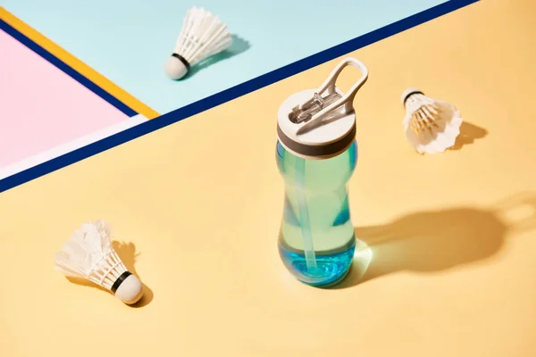 Bouteille d'eau et navettes de badminton à la surface avec des lignes colorées — Photo de stock