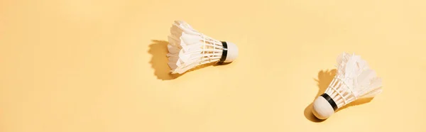 Two badminton shuttlecocks with shadow on yellow surface, panoramic shot — Stock Photo