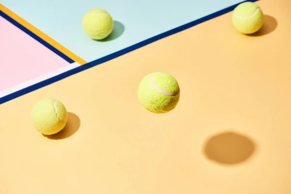 Высокий угол обзора теннисных мячей с тенью на красочном фоне с голубыми линиями — стоковое фото